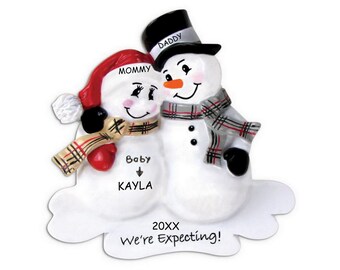 May include: A white snowman couple ornament with a red hat and scarf on the female snowman and a black top hat and gray scarf on the male snowman. The ornament says "Mommy", "Daddy", "Baby Kayla", "20XX", and "We're Expecting!"