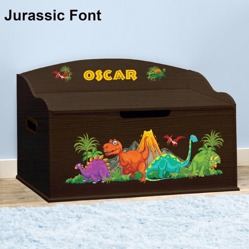 May include: A brown wooden toy chest with a dinosaur theme. The chest has a hinged lid and a personalized nameplate that reads "OSCAR". The front of the chest features a colorful illustration of dinosaurs, a volcano, and palm trees.