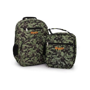 May include: A green and black camouflage backpack and matching lunch bag set. The backpack has a large main compartment and a front pocket. The lunch bag has a top handle and a front zipper pocket. Both items have the name "Wyatt" in orange.