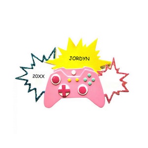 May include: Pink video game controller ornament with a yellow starburst behind it that says "JORDYN" and a blue starburst behind it that says "20XX".
