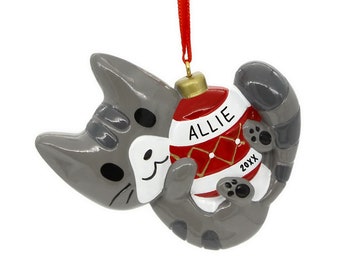 May include: A grey ceramic Christmas ornament shaped like a cat holding a red and white striped bauble with the name "Allie" and the year "20XX" on it.