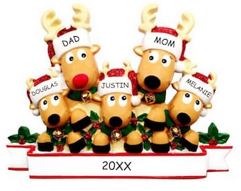 May include: A Christmas ornament featuring five reindeer with red Santa hats. The reindeer are stacked on top of each other with the top reindeer's head peeking over the others. The reindeer are wearing green and gold collars with bells. The ornament has a banner at the bottom with the text "20XX" and the names "Dad", "Mom", "Douglas", "Justin", and "Melanie".