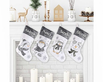 May include: Four white Christmas stockings with gray fur trim, personalized with the names "Andrew", "Nancy", "Sarah", and "Oliver". Each stocking features a different embroidered design: a snowman, Santa Claus, a penguin, and a reindeer.