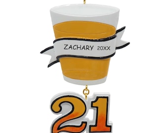 Op de afbeelding: Een hangend ornament in de vorm van een geel bierglas met een witte rand en voet. Een witte banner in het midden bevat de zwarte tekst ZACHARY 20XX. Onder het glas staat het getal 21 in oranje met een zwarte omlijning.