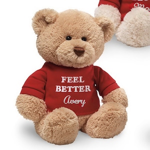 May include: A brown teddy bear wearing a red shirt with the text "Feel Better Avery" embroidered on it.