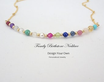 May include: A gold chain necklace with colorful gemstone beads. The necklace features a variety of birthstone colors, including red, purple, green, and blue. The text "Family Birthstone Necklace" and "Design Your Own Personalized Jewelry" is displayed.