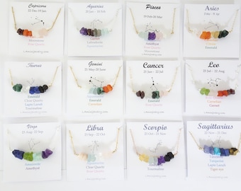 May include: A collection of gold-toned necklaces, each featuring a row of colorful gemstones. Each necklace is displayed on a white card with a zodiac sign, constellation illustration, and gemstone names. The website address is also visible.