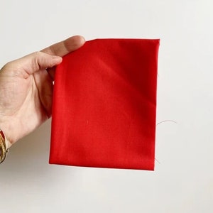 May include: A solid red fabric swatch. The fabric is smooth and has a slight sheen.