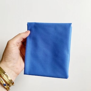 Può includere: Un pezzo di stoffa blu tinta unita piegato.