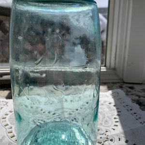 May include: A vintage green glass mason jar with a metal lid. The jar has the words "MASON" and "QUART" embossed on the side.