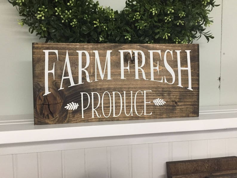 K&ouml;nnte beinhalten: Ein rustikales Holzschild mit dem Text "FARM FRESH PRODUCE" in wei&szlig;er Farbe. Das Schild hat eine braune Holzmaserung und ist perfekt f&uuml;r ein Bauernhaus oder eine Landhausk&uuml;che.