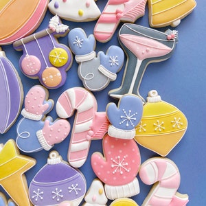 Pode incluir: Conjunto de biscoitos de a&ccedil;&uacute;car tem&aacute;ticos de Natal coloridos decorados com glac&ecirc; e granulado. Os biscoitos incluem enfeites, luvas, bengalas de doces e &aacute;rvores de Natal.