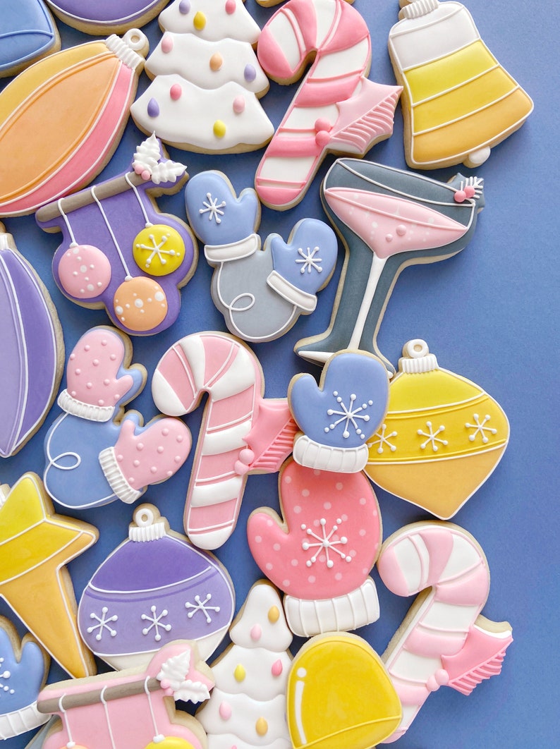 Pode incluir: Conjunto de biscoitos de a&ccedil;&uacute;car tem&aacute;ticos de Natal coloridos decorados com glac&ecirc; e granulado. Os biscoitos incluem enfeites, luvas, bengalas de doces e &aacute;rvores de Natal.