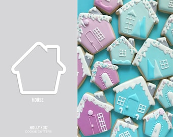 May include: A set of cookie cutters in the shape of a house. The cutters are made of metal and have a silver finish. The cutters are shown on a gray background with a blue background behind the cutters. The image also shows examples of cookies cut with the cutters, decorated with frosting and sprinkles.