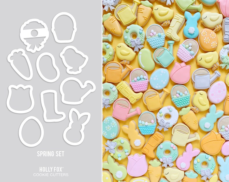 May include: A set of 12 spring-themed cookie cutters, including a bunny, a watering can, a flower, a boot, a basket, a chick, a carrot, a wreath, a  pail, a  donut, a  pear, and an egg. The cutters are made of white metal and are arranged on a gray background. The text "SPRING SET" and "HOLLY FOX COOKIE CUTTERS" is printed below the cutters.
