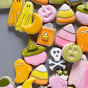 May include: A collection of Halloween-themed sugar cookies decorated with colorful icing. The cookies feature various designs, including ghosts, pumpkins, candy corn, witches' hats, and a skull and crossbones.