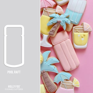 May include: A white cookie cutter shaped like a pool raft. The cookie cutter is on a gray background. The text "POOL RAFT" is below the cookie cutter. The text "HOLLY FOX COOKIE CUTTERS" is below the text "POOL RAFT".