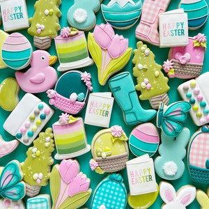 May include: A collection of colorful Easter-themed sugar cookies decorated with various designs, including bunnies, eggs, flowers, and the phrase "Happy Easter".