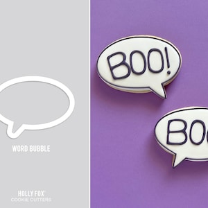 May include: Two Halloween-themed cookies in the shape of speech bubbles, each with the word "BOO!" in dark blue. The cookies have a white base with a dark blue outline and are set against a purple background. A cookie cutter is also shown.