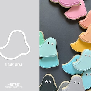 May include: A white outline of a ghost cookie cutter with the text "Floaty Ghost" and "HOLLY FOX COOKIE CUTTERS" below. The image also shows a variety of colorful ghost-shaped cookies with different colored icing.