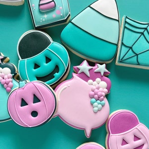 May include: Assortment of Halloween-themed sugar cookies decorated with teal, pink, and white icing. The cookies feature various designs, including pumpkins, ghosts, candy corn, and a shopping bag.