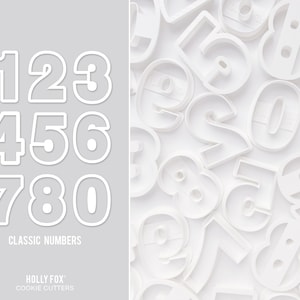 May include: White plastic cookie cutters shaped like the numbers 1 through 0. The cutters are arranged in three rows of three. The text "CLASSIC NUMBERS" is below the cutters. The text "HOLLY FOX COOKIE CUTTERS" is below the text "CLASSIC NUMBERS".