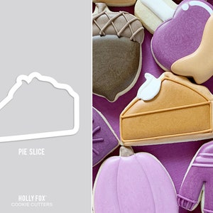 May include: A white plastic cookie cutter in the shape of a slice of pie. The cutter is on a gray background. The text "Pie Slice" is below the cutter. The text "HOLLY FOX" and "COOKIE CUTTERS" is below the text "Pie Slice".