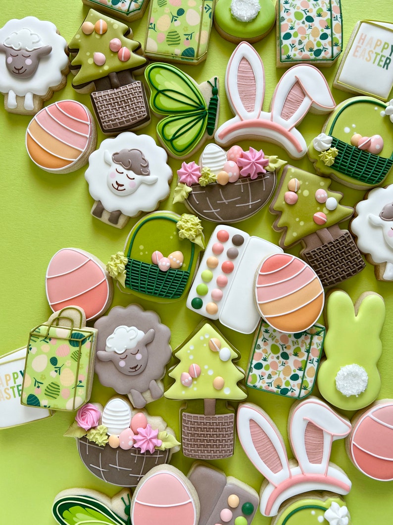 May include: A collection of Easter-themed sugar cookies decorated with various designs, including bunnies, lambs, baskets, eggs, and trees. The cookies are on a green background.