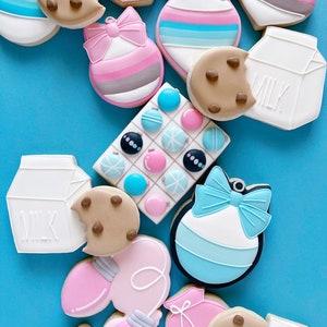 May include: Assortment of Christmas-themed sugar cookies decorated with various colors and designs, including ornaments, milk cartons, and a cookie with chocolate chips.