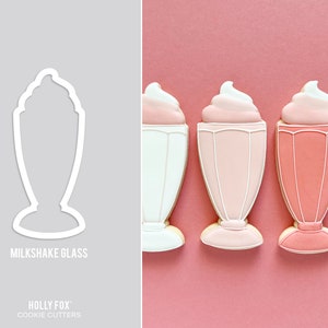 Peut inclure: Trois biscuits en sucre glacés roses et blancs en forme de verres à milkshake. Les biscuits sont sur un fond rose.  "MILKSHAKE GLASS" et "HOLLY FOX COOKIE CUTTERS" sont imprimés sous les biscuits.