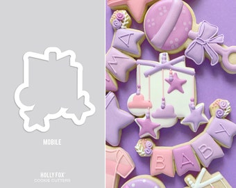 May include: A set of purple, pink, and white cookie cutters shaped like a baby mobile, a rattle, and a banner that says "BABY".