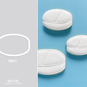 May include: Three white cookie cutters shaped like pills, with a line down the middle. The cookie cutters are on a blue background. The text "TABLET" is below the cookie cutters.