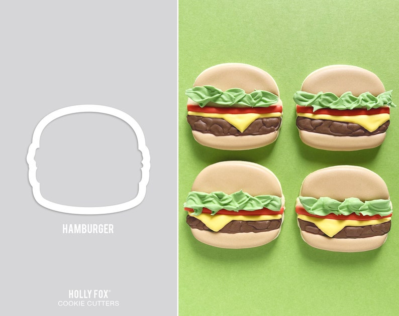 K&ouml;nnte beinhalten: Vier dekorierte Zuckerkekse in Form von Hamburgern. Jeder Keks hat ein braunes Patty, gelben K&auml;se, gr&uuml;nen Salat und eine rote Tomate. Die Kekse befinden sich auf gr&uuml;nem Hintergrund. Der Text "HAMBURGER" ist unter dem Ausstecher gedruckt.