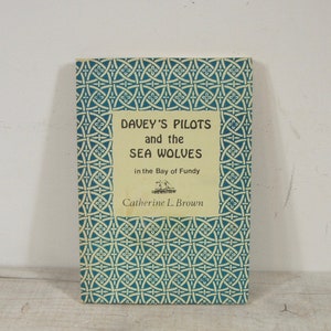 May include: A vintage book titled "Davey's Pilots and the Sea Wolves in the Bay of Fundy" by Catherine L. Brown. The cover features a blue and white geometric pattern.