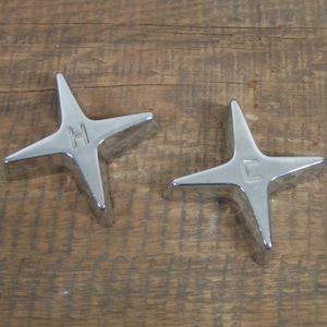 May include: Two silver star-shaped faucet handles with the letters "H" and "C" engraved on them.