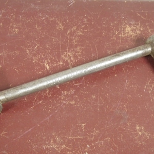 May include: A vintage metal wrench with a long handle and a square socket on one end and a rounded head on the other end.