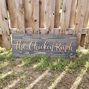 May include: A rustic wooden sign with the text "The Chicken Ranch" in a cursive font.