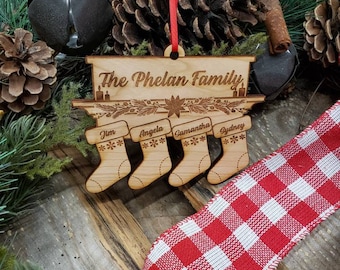 May include: Wooden Christmas ornament with the text "The Phelan Family" and four stockings with the names "Jim", "Angela", "Samantha", and "Sydney" on a rustic wooden background.