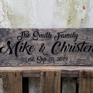 May include: A dark brown wooden sign with the text "The Smith Family Mike & Christen est. Sep 28, 2019" carved into it.