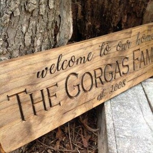 May include: A rustic wooden sign with the text "Welcome to our home, The Gorgas Family est. 2008" carved into the surface.