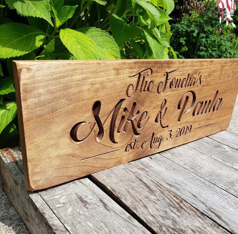 May include: A wooden sign with the text "The Fonecha's Mike & Paula est. c Aug. 3, 2019" carved into it.