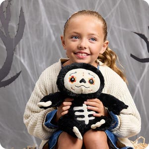 May include: A plush sloth toy with black fur, a white face featuring a colourful floral sugar skull design, and a white skeleton rib cage graphic on its chest. The sloth has long arms with white claws and a soft, rounded body structure.