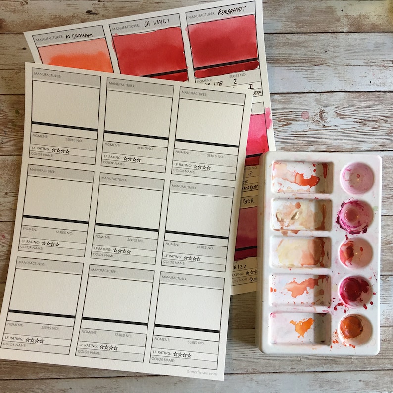May include: Watercolor paint swatches and a white palette with various shades of red, orange, and pink. The swatches are labeled with manufacturer names like Da Vinci and Rembrandt. The palette has several paint wells with different colors.