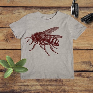 May include: A heather grey t-shirt with a vintage illustration of a bee in maroon.