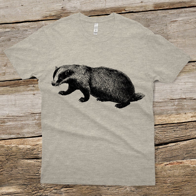 Puede incluir: Una camiseta gris jaspeada con una ilustraci&oacute;n en blanco y negro de un tej&oacute;n.