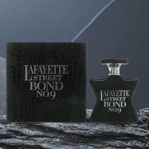 May include: Black perfume bottle and box set. The bottle has a unique shape with a silver cap. The box and bottle both feature the text "LAFAYETTE STREET BOND NO.9" in silver lettering. The box has a textured, embossed pattern.