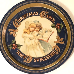 Puede incluir: Bandeja redonda vintage de "Christmas Carol" con borde azul oscuro y ribete dorado. El centro presenta una ilustración de dos niños cantando de un libro, con las palabras "Christmas Carol" que rodean la imagen.