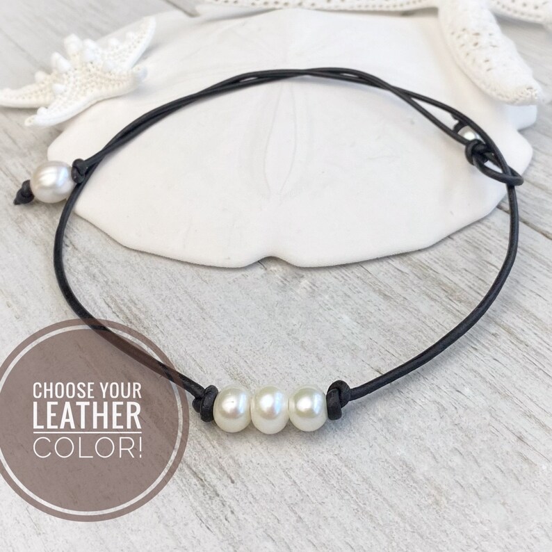 May include: A simple black leather choker necklace with three white pearls. The text "Choose Your Leather Color!" is visible in the image.
