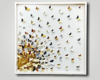 May include: A white framed wall art piece featuring a cluster of silver, gold, and brown butterflies arranged in a cascading pattern on a white background.