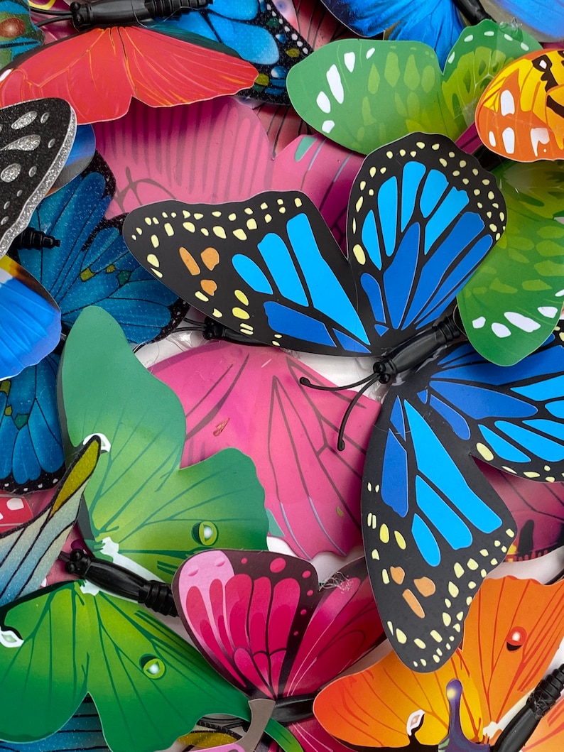 May include: A collection of colorful butterfly decorations with various patterns and designs. The butterflies are made of paper or plastic and have a 3D effect. They are perfect for adding a touch of whimsy to any space.